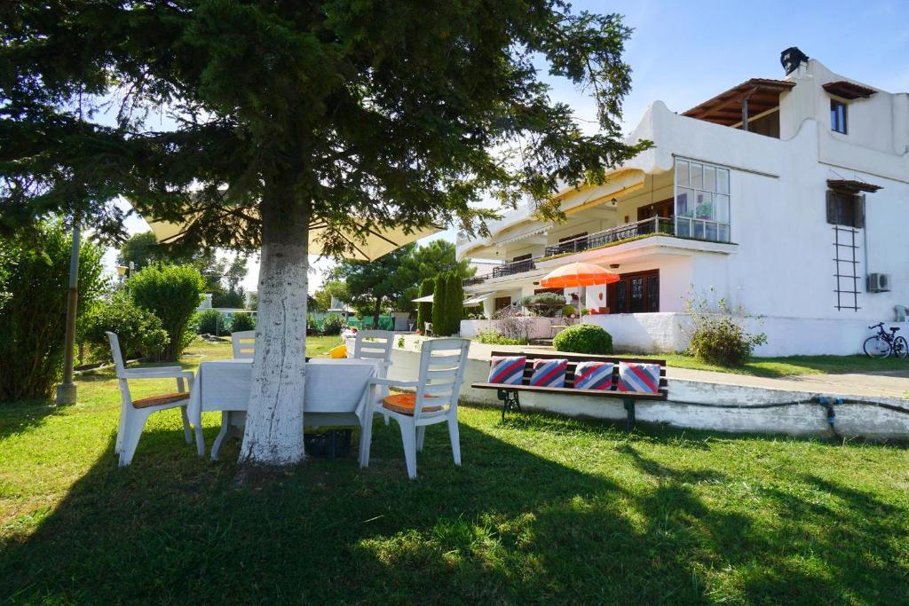 a table and chairs under a tree in front of a house at Solon and Teo Summer House in Avdira beach in Paralía Avdhíron