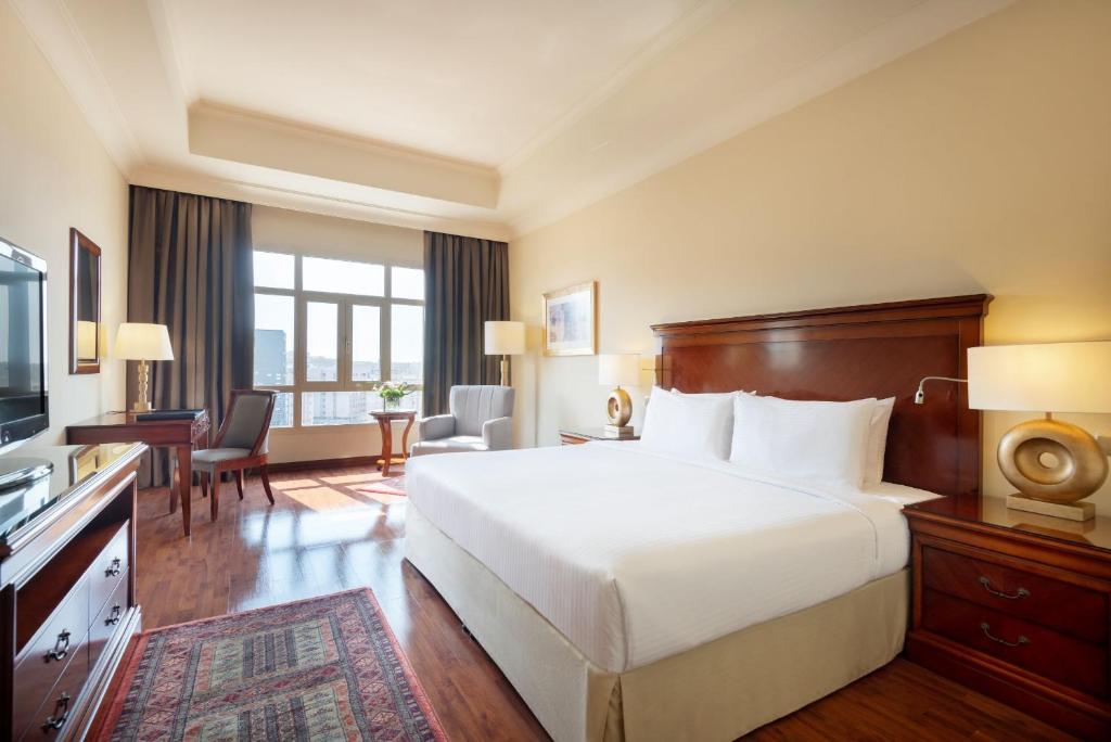 a hotel room with a bed and a television at Concorde Hotel Doha in Doha