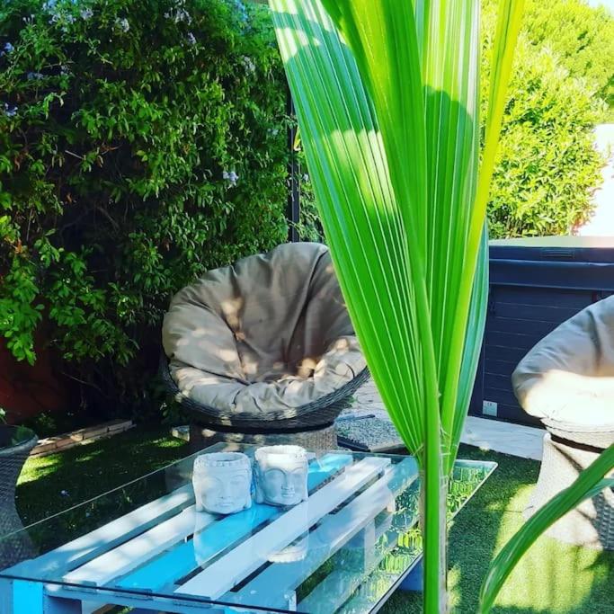 a glass table with two candles on it next to a plant at Hébergement insolite studio Grau du Roi Mas des Marines Piscine in Le Grau-du-Roi