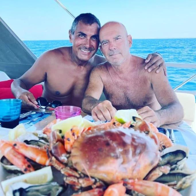 two men sitting at a table with a pile of seafood at Hébergement insolite studio Grau du Roi Mas des Marines Piscine in Le Grau-du-Roi