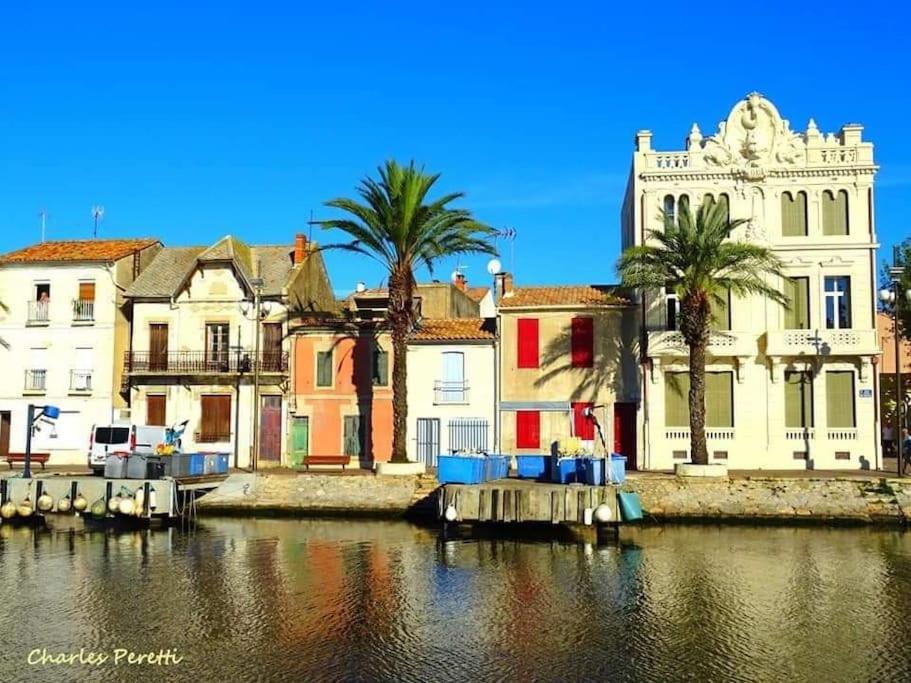 a group of buildings next to a body of water at Hébergement insolite studio Grau du Roi Mas des Marines Piscine in Le Grau-du-Roi