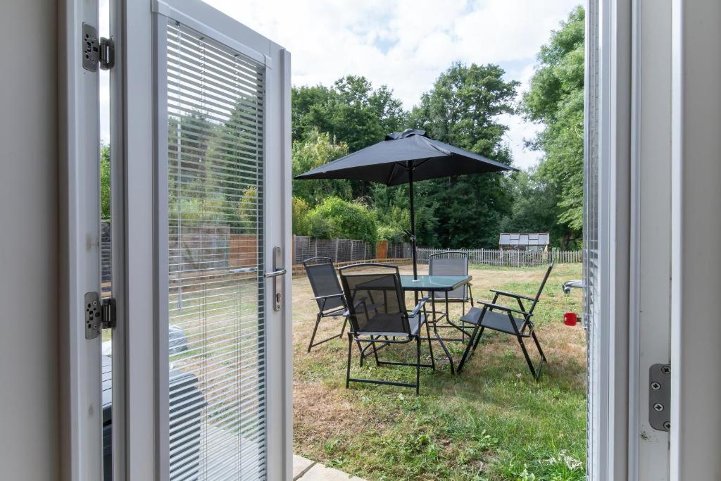 a patio door with a table and chairs and an umbrella at Cozy One Bedroom Cottage With Spacious Garden +BBQ in Brasted