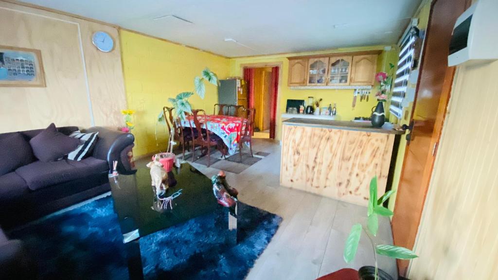 a living room with a couch and a kitchen at Casa acogedora, a minutos del Lago Llanquihue. in Llanquihue
