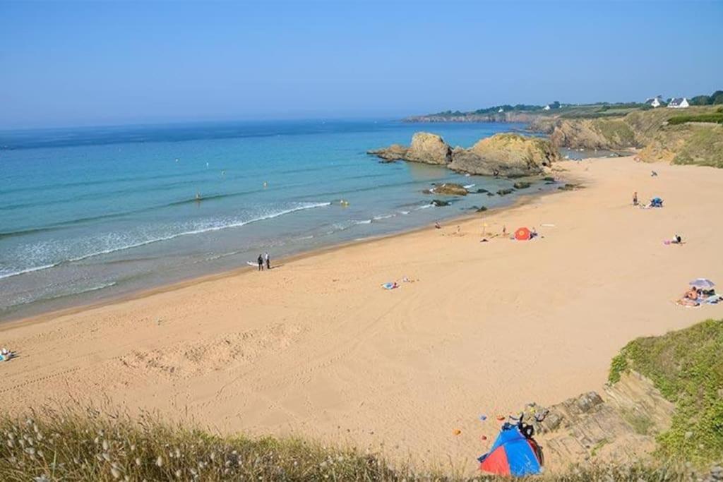 a beach with people on the sand and the ocean at Bel appartement, proche plages pour 4 personnes, 2 chambres in Clohars-Carnoët