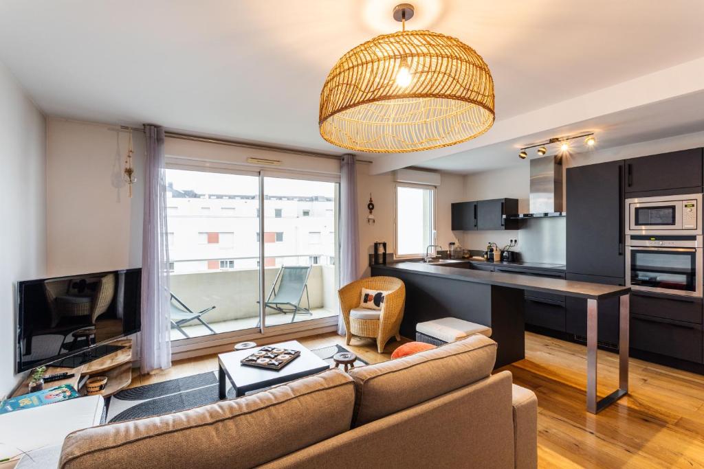 ein Wohnzimmer mit einem Sofa und einer Küche in der Unterkunft Le ViLoNa - T3 moderne avec parking privé in Rennes