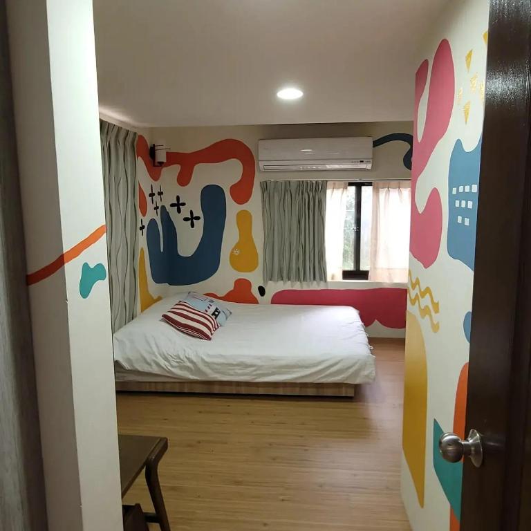 a small bedroom with a bed and a wall with a mural at Taipei Jinguashi Cloud Mountain Homestay B&amp;B in Jiufen