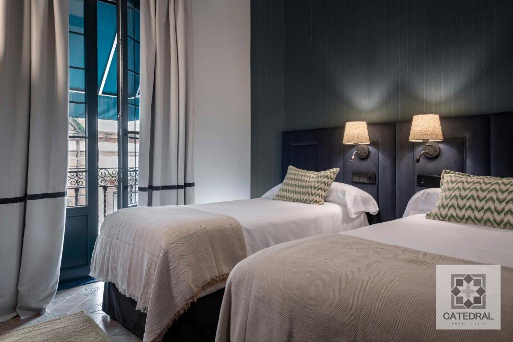 a hotel room with two beds and a window at Casa Catedral in Seville