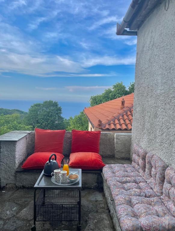 eine Terrasse mit roten Kissen, einem Tisch und einem Sofa in der Unterkunft Βουνό και Θάλασσα I in Xorychti