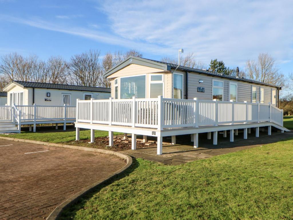 un mobile home avec une terrasse couverte et une maison dans l'établissement 17 Summer Meadows, à Ashington