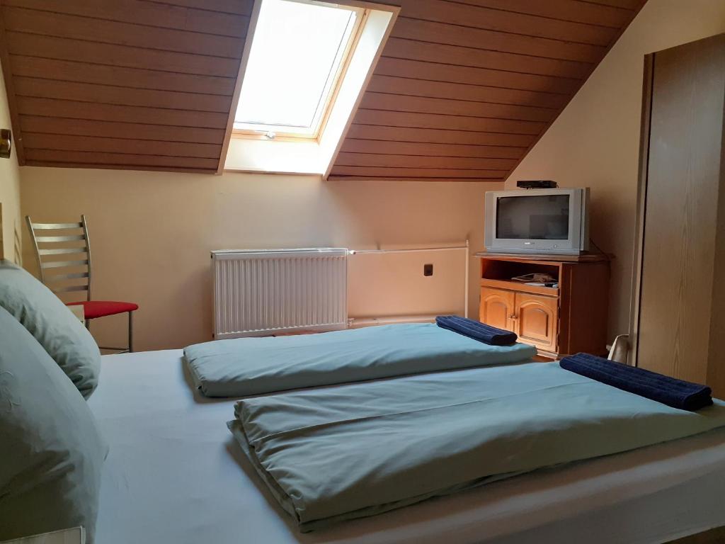 a bedroom with three beds and a tv and a window at Csilla Haus in Bük
