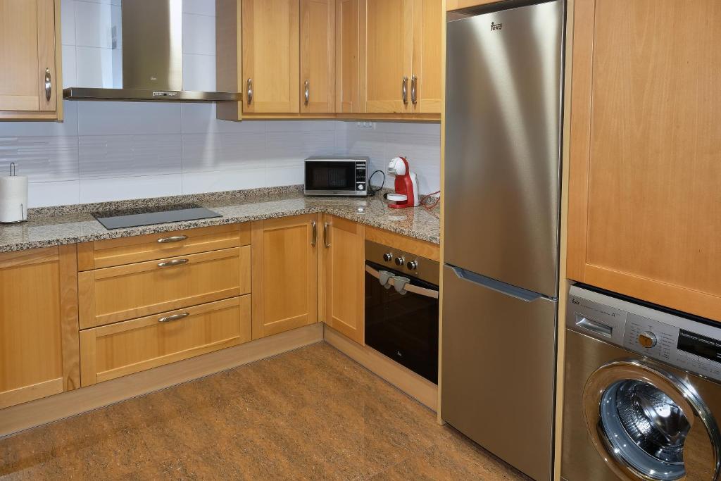 a kitchen with wooden cabinets and a stainless steel refrigerator at ANCLA spaces CON VISTAS AL MAR EGVT436CS in Vinaròs