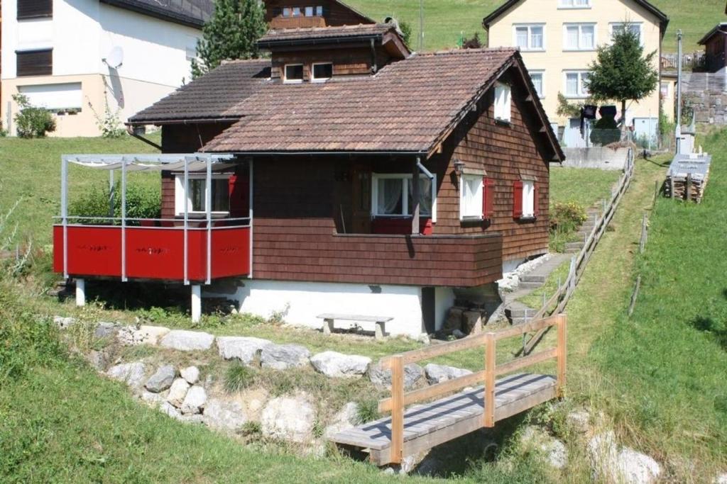 a small house with a wooden roof on a hill at Unterkunft MECK-HEI in Wildhaus