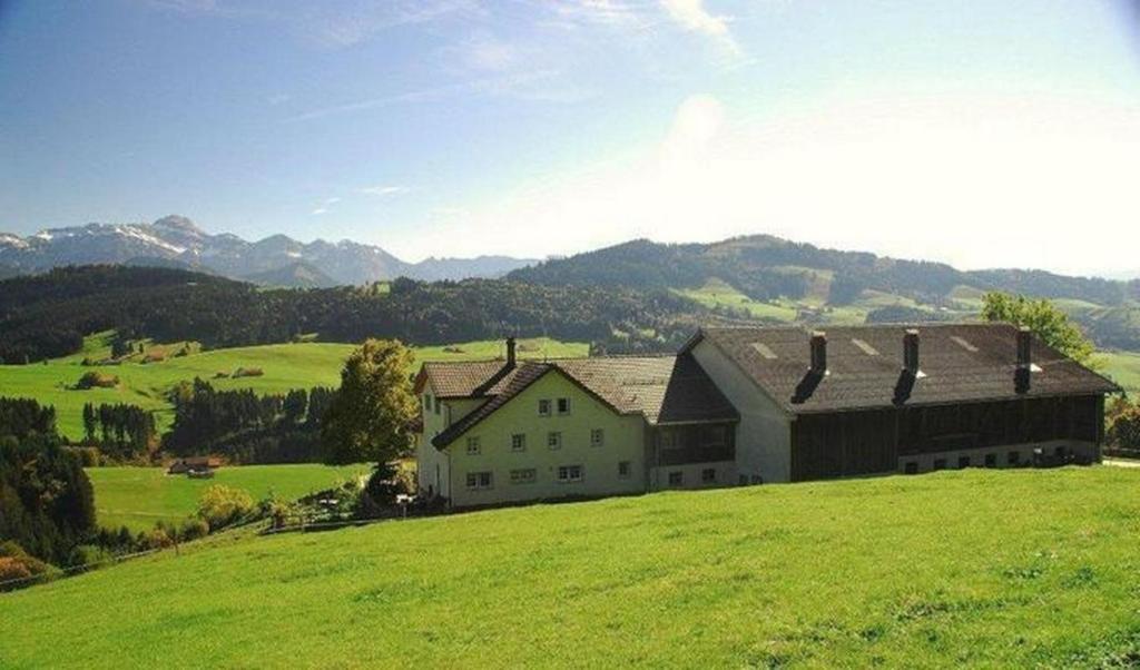 une grande maison sur une colline dans un champ verdoyant dans l'établissement Hof Stein Schwellbrunn, à Schwellbrunn