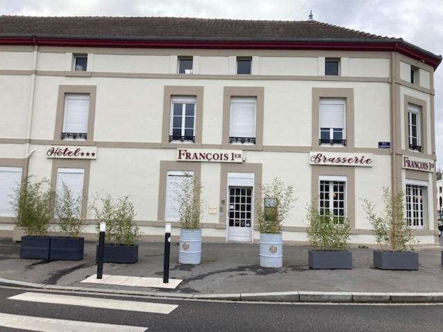 un grand bâtiment blanc avec des plantes devant lui dans l'établissement Hôtel François 1er, à Saint-Dizier