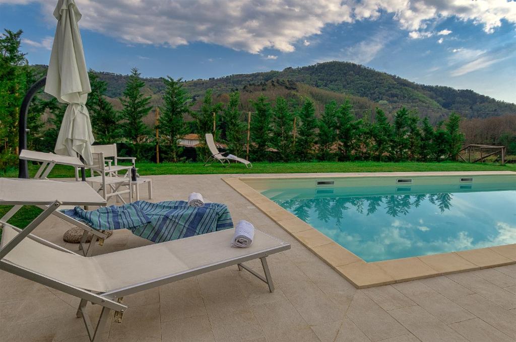 - Piscina con sillón y sombrilla en Villa Cristina modern farmhouse with Private Pool, en Monsagrati