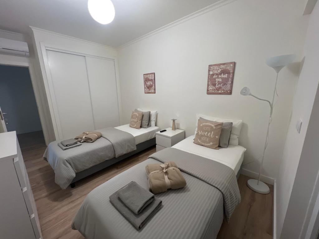 two beds in a room with white walls and wood floors at Modern Twin Room with a balcony in Montijo