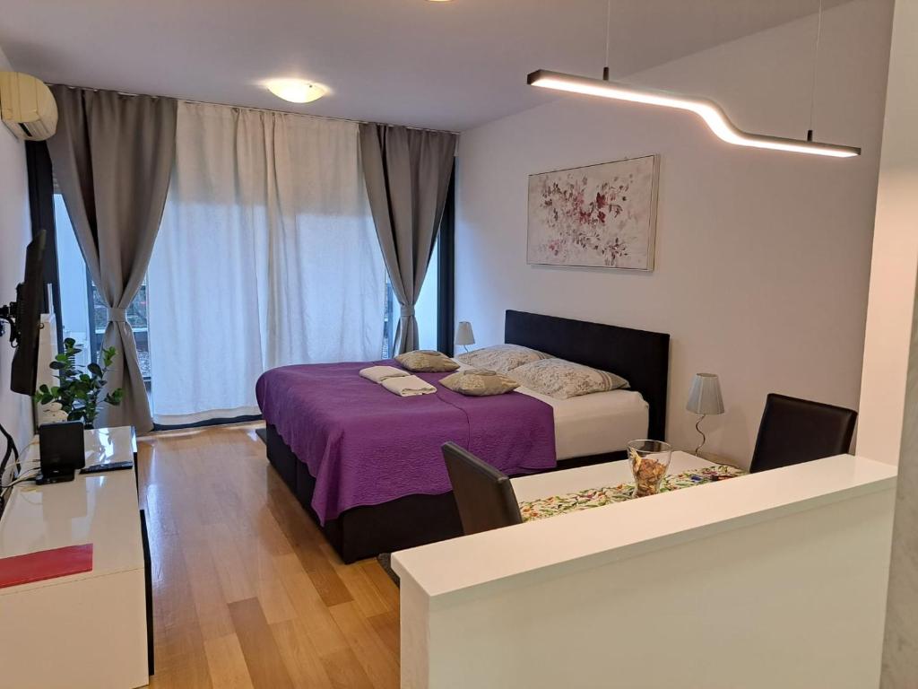 a bedroom with a bed with purple sheets and a window at Nova Galerija West App Dora in Zagreb