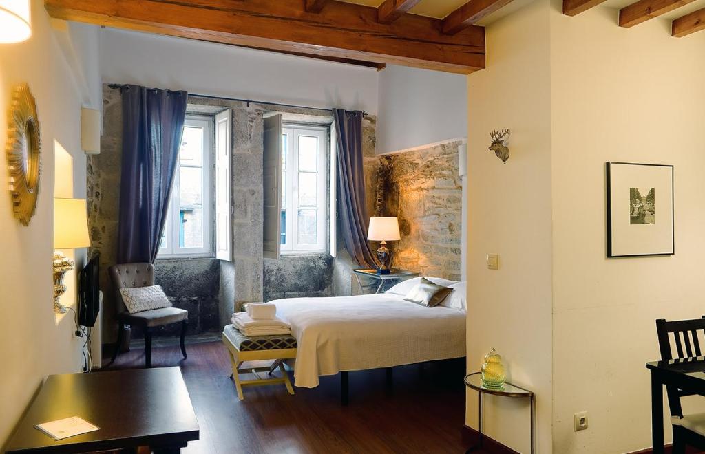 a bedroom with a bed and a chair in a room at Inicia Casas Reales in Santiago de Compostela