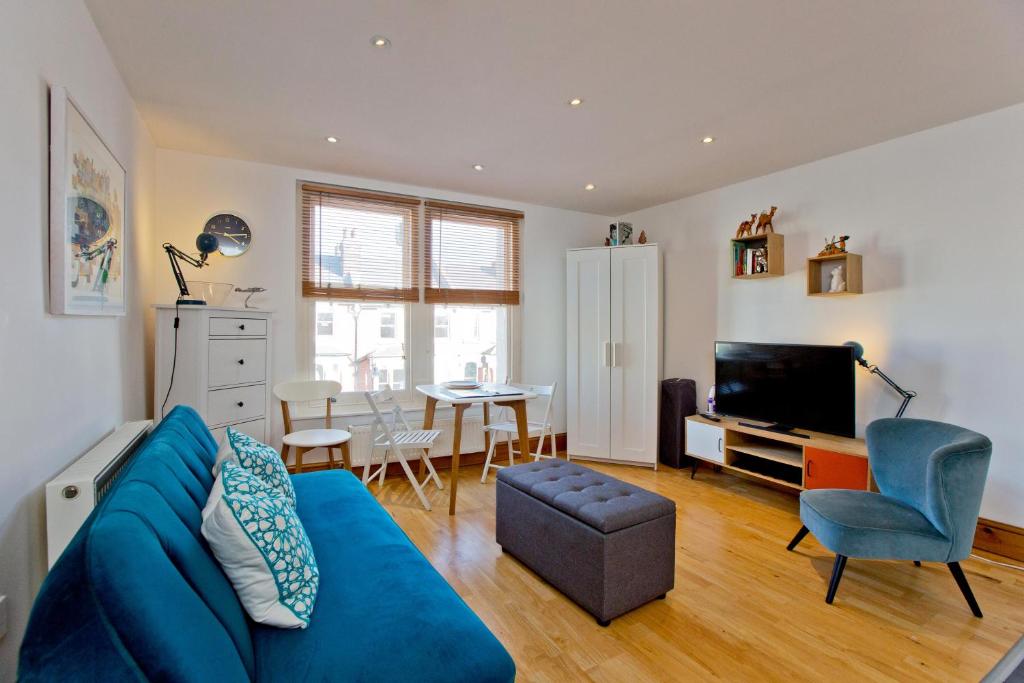 ein Wohnzimmer mit einem blauen Sofa und einem Tisch in der Unterkunft Convenient 1 bedroom apartment with parking in London