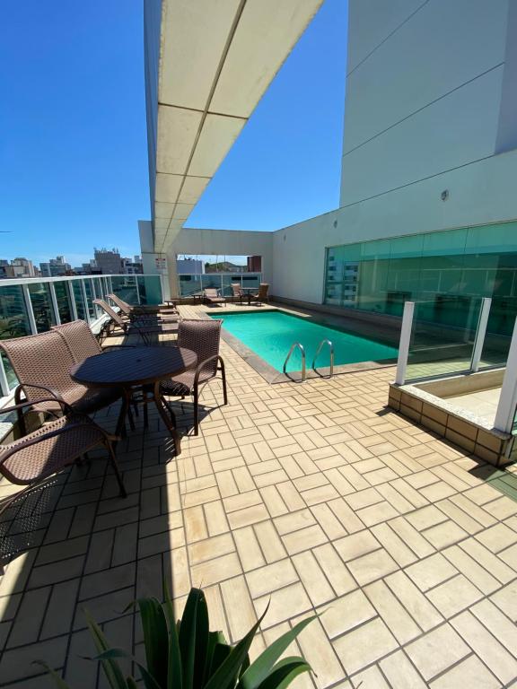 eine Terrasse mit einem Tisch und Stühlen sowie einem Pool in der Unterkunft Praia do Canto Apart Hotel in Vitória