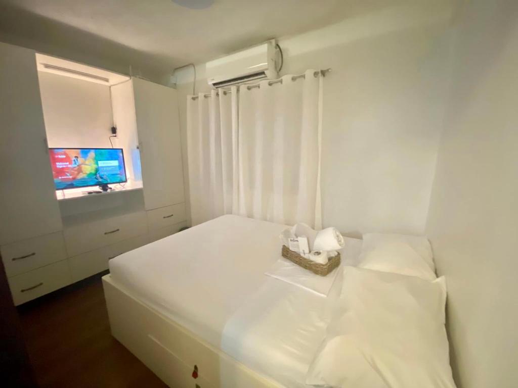 a white bedroom with a white bed with a television at Tiny Room Hura Homes II Condominium Unit Visayas Avenue QC in Manila