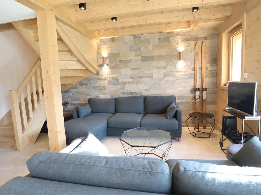- un salon avec un canapé bleu et un mur en pierre dans l'établissement Chalet Neuf Exposé Plein Sud à 600m des Pistes avec Terrasse et Parking - FR-1-623-299, aux Gets
