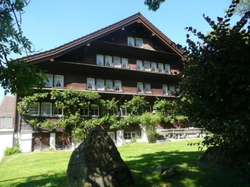um grande edifício com uma grande rocha em frente em Gast- & Ferienhaus Frohheim em Sankt Peterzell