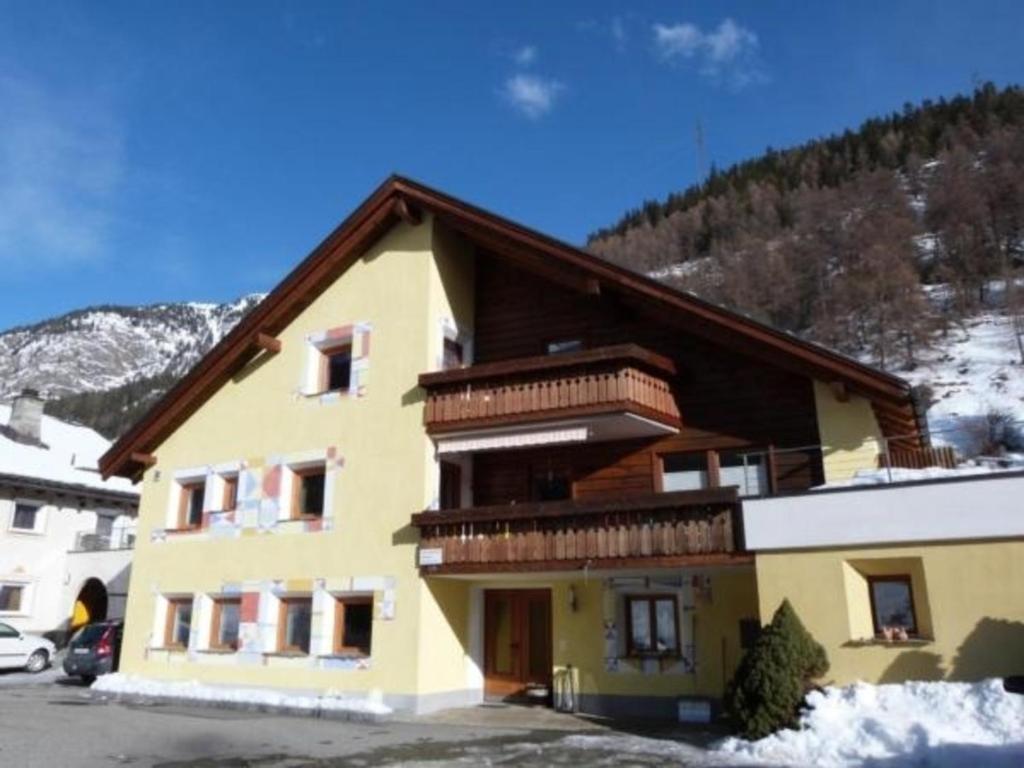 a large yellow building with snow on a mountain at Ers Curtins in Zernez