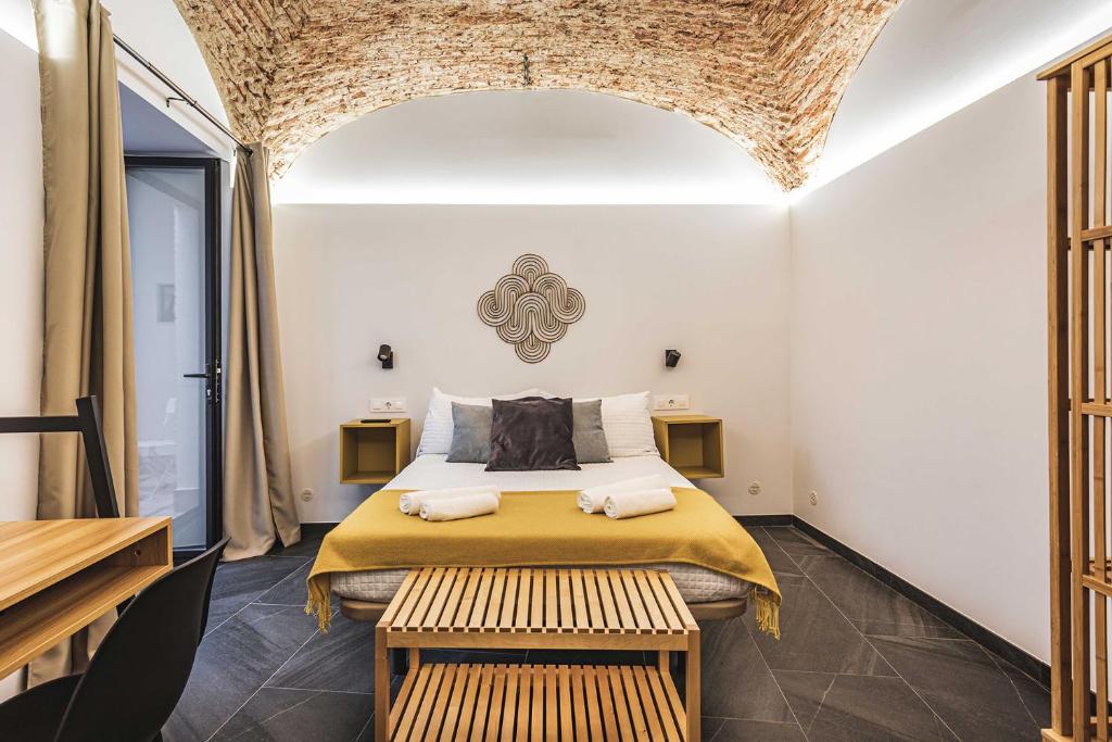 a bedroom with a bed and two benches in a room at Apartamentos Cáceres Central Suites "Torres de Cáceres" in Cáceres