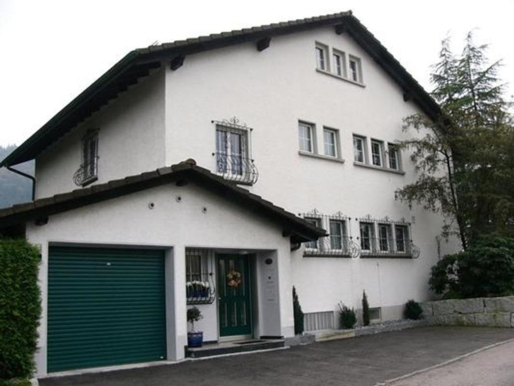 a white house with green doors and a garage at Gästewohnung Matthöhe in Lucerne