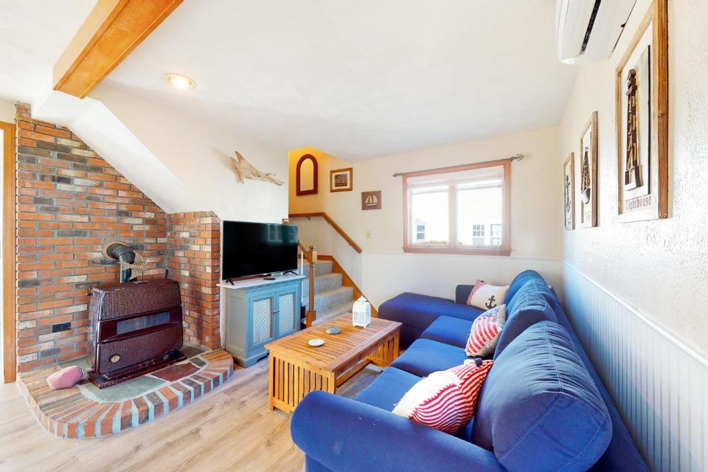 sala de estar con sofá azul y chimenea en Swift Beach House, en Wareham
