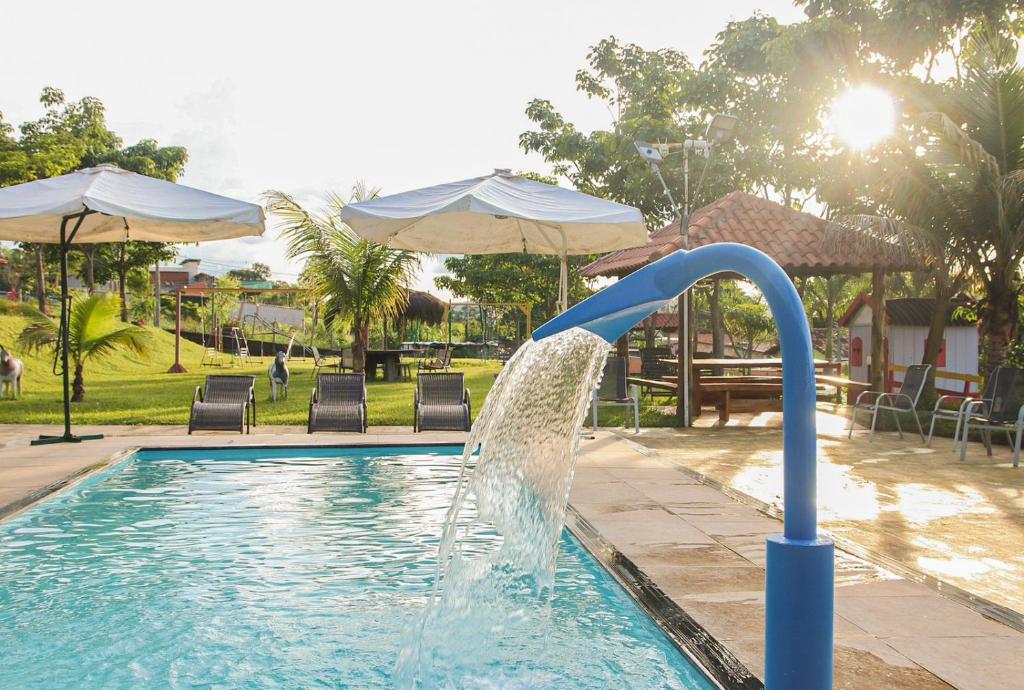 a water slide in a swimming pool with umbrellas at Pousada do Dinho in Esmeraldas