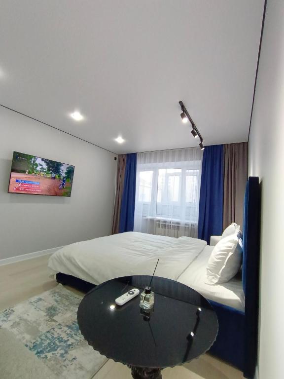 a bedroom with a bed and a table with a remote control at Квартира Алия in Aktobe