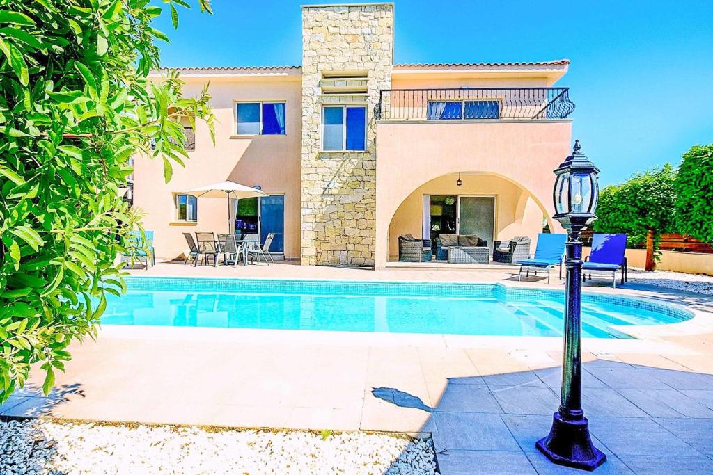 a villa with a swimming pool and a house at Villa Golden Coral in Peyia