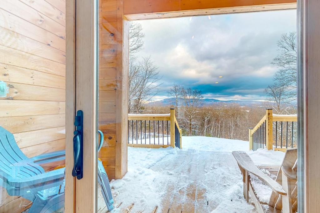 a door to a cabin with snow on the porch at The Alpine Outlook in Londonderry