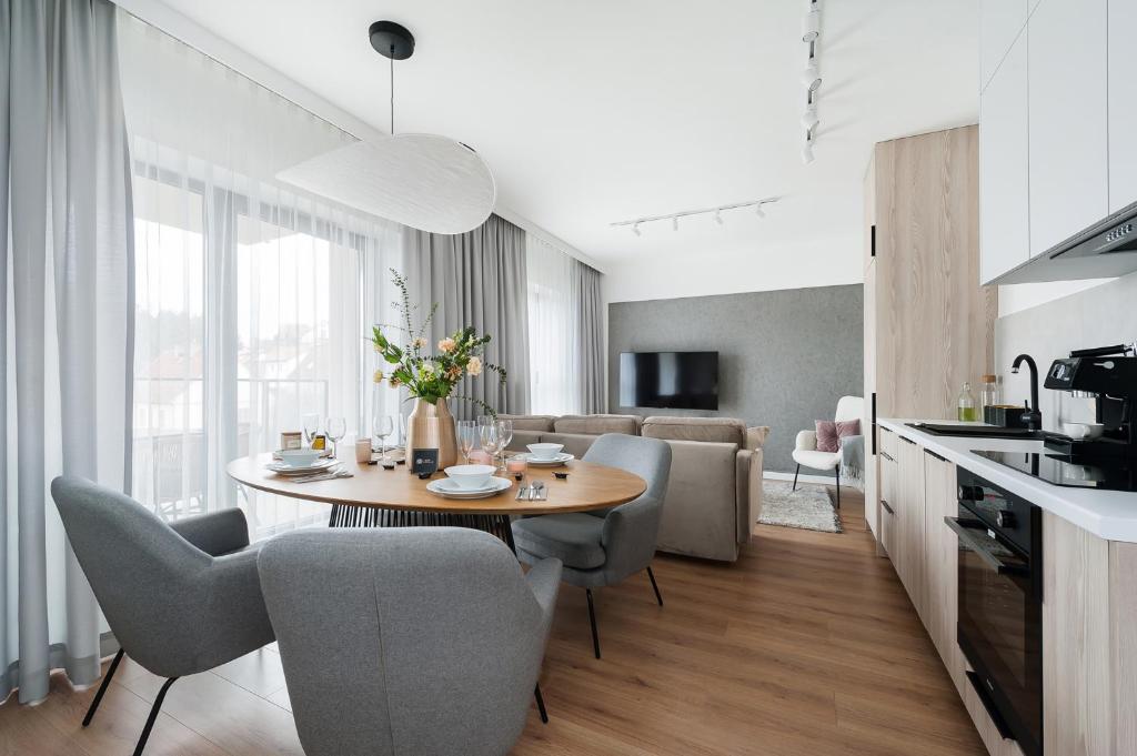 a kitchen and living room with a table and chairs at Lake Club Apartments by LoftAffair in Mikołajki