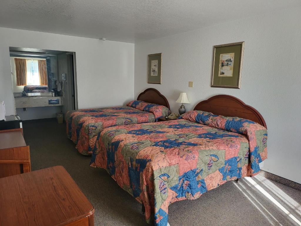 ein Hotelzimmer mit 2 Betten und einem Tisch in der Unterkunft Blue Ribbon Inn and Suites in Sallisaw