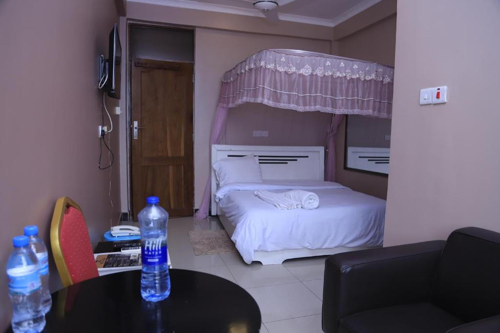 達累斯薩拉姆的住宿－B10 Airport Lodge，一间卧室配有一张床和一张桌子,并提供2瓶水