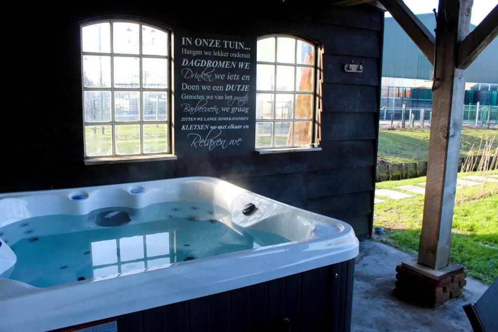 a jacuzzi tub with a sign on the wall at Wellness Bed & Breakfast by Leef in Maasland