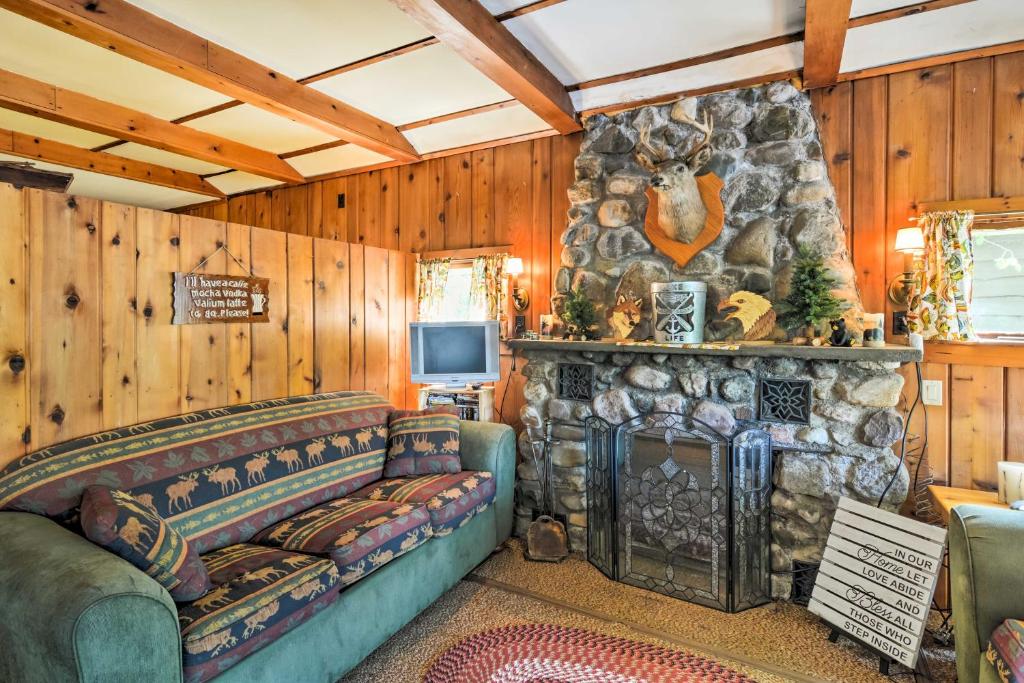 a living room with a couch and a stone fireplace at 11 Mi to Snow Snake Ski! Lake House with Boat Dock in Lake