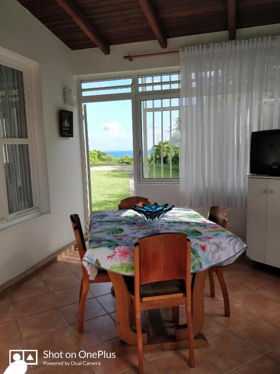 a dining room with a table and chairs and a window at Cocooning sur mer Bungalow in Sainte-Anne