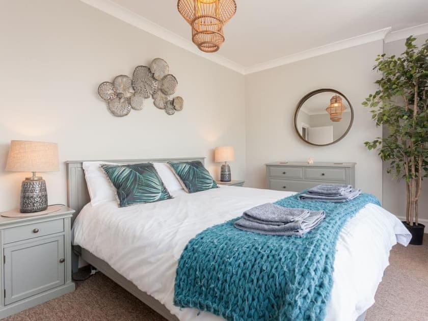 a bedroom with a bed with a blue blanket on it at 2TheVilla - Great views, 3 bedrooms, parking, central location in Ilfracombe
