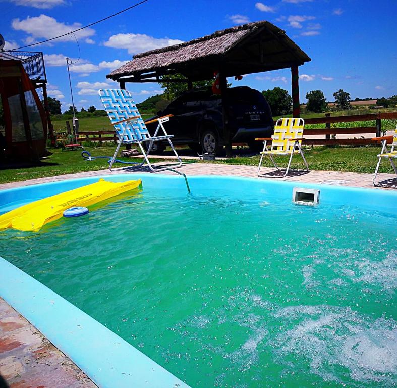 uma piscina com duas cadeiras e um gazebo em Quinta en Alvear em General Alvear