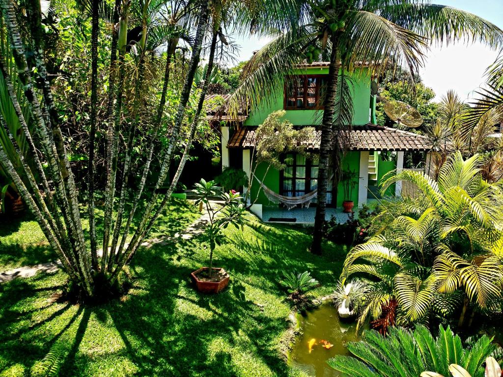 ein grünes Haus mit Palmen davor in der Unterkunft Casa das Carpas in Arraial d'Ajuda