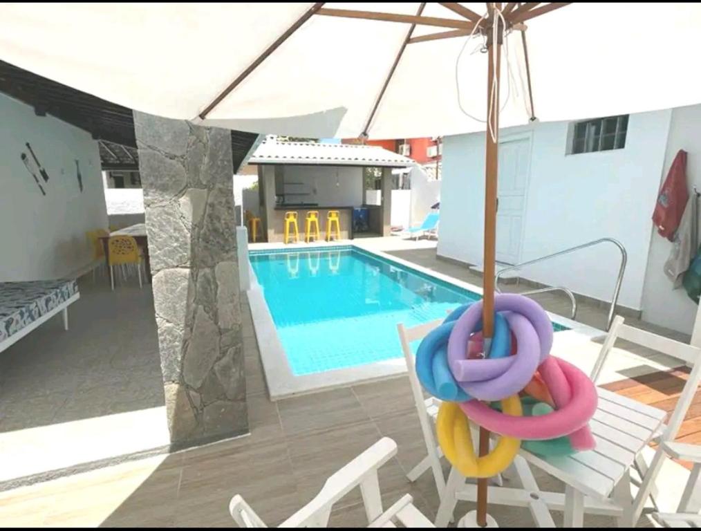 einen Pool mit Stühlen, einem Sonnenschirm und einem Pool in der Unterkunft Guarajuba Sereia House in Guarajuba
