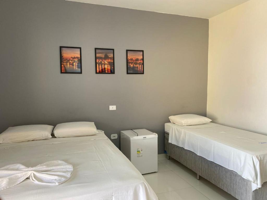 twee bedden in een kamer met drie foto's aan de muur bij Portal do Sol in Itaberaba