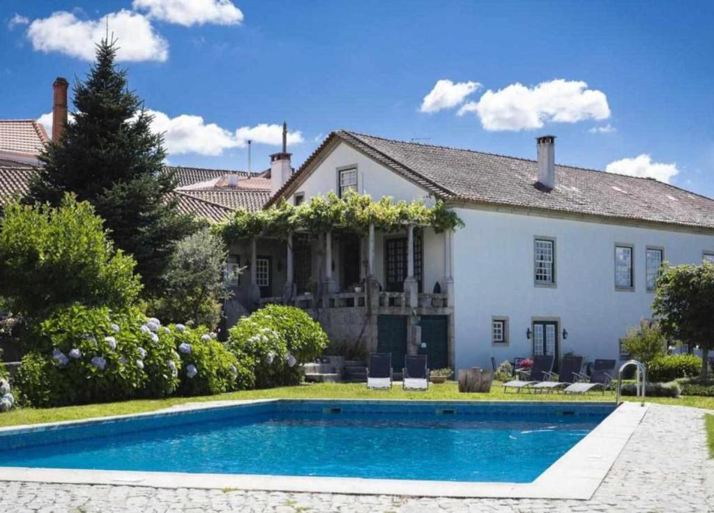 uma casa com uma piscina em frente em Casa de Santa Ana da Beira em Seia