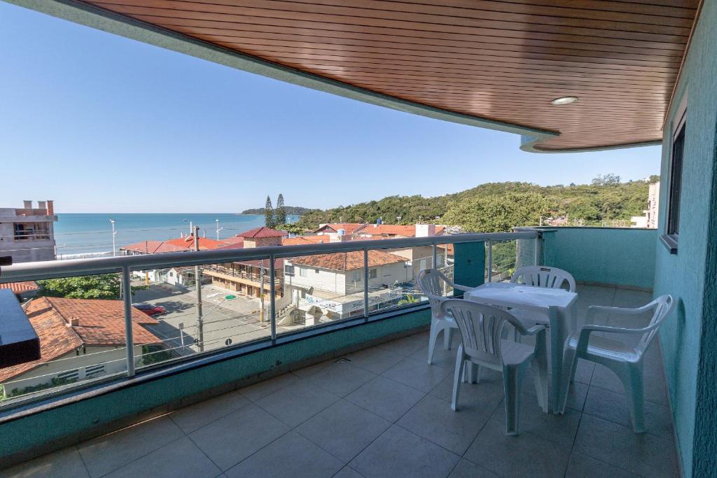 balcón con mesa, sillas y vistas al océano en Aluguel Apartamento 3 quartos sendo 1 suíte em Bombinhas, en Bombinhas