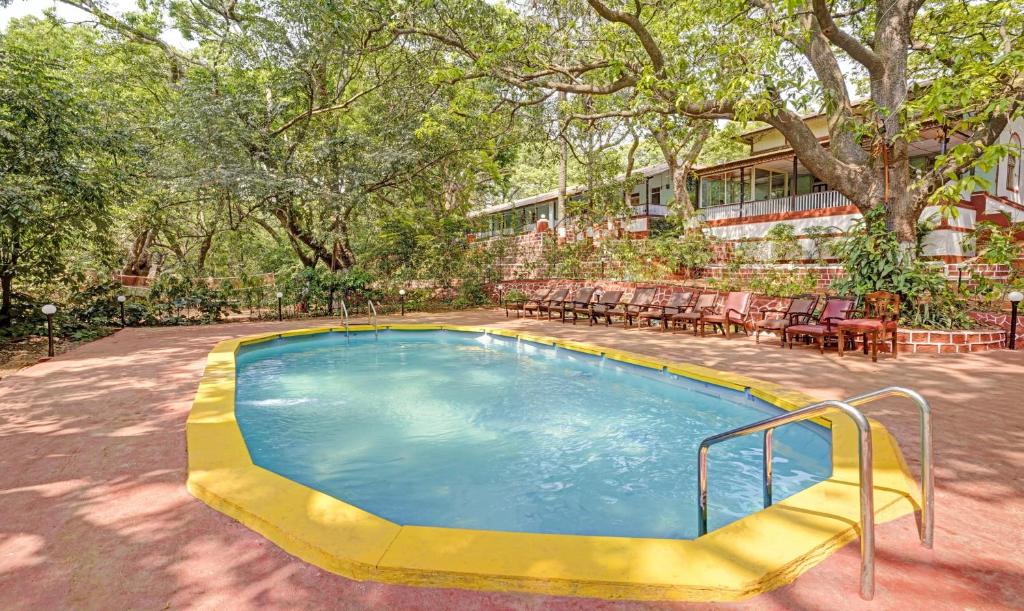a swimming pool with chairs and a building at Treebo Trend Cecil Resort 600 Mtrs From Matheran Railway Station in Matheran