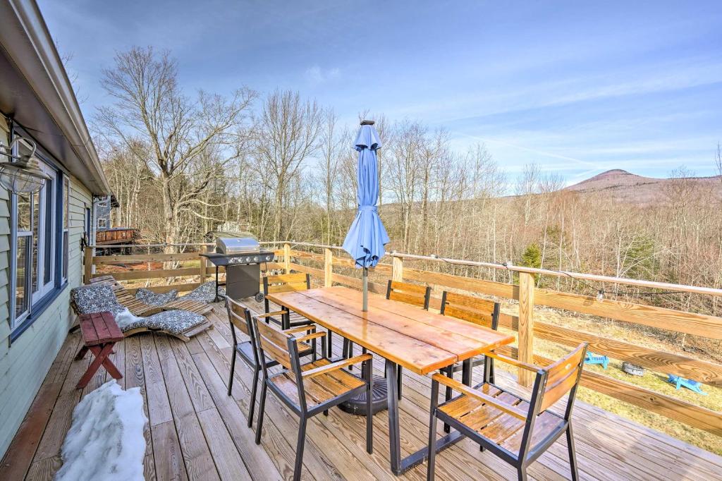 a wooden table and chairs on a deck with an umbrella at Catskills Cottage with Deck, 7 Mi to Hunter Mtn in Elka Park